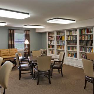 A cozy library room with bookshelves, a reading table, and comfortable seating.