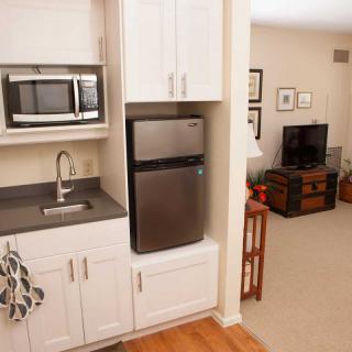 A compact kitchenette with a microwave, refrigerator, and sink adjacent to a cozy living room.