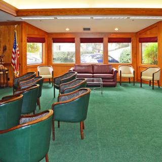 A meeting room with green carpet, arranged seating, and large windows.