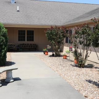 A serene outdoor space featuring a pathway leading to a comfortable home surrounded by greenery.