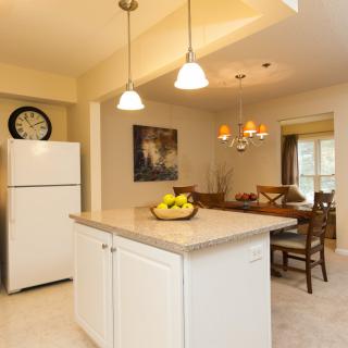 A cozy kitchen and dining area featuring an island counter with pendant lights, a refrigerator, and a chandelier over the dining table.
