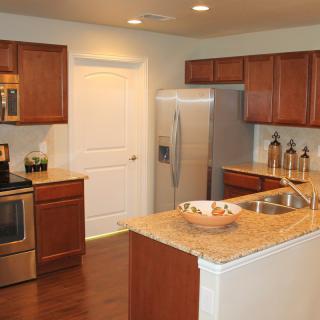 A modern kitchen featuring wooden cabinets, stainless steel appliances, and a marble countertop.