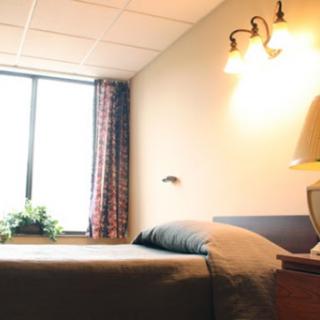 A cozy hospital room featuring a bed, window, and decorative touches.