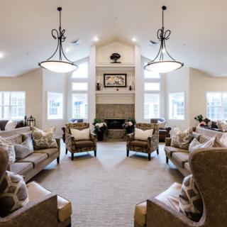 A spacious and elegantly designed living room featuring plush seating, a central fireplace, and stylish chandeliers.