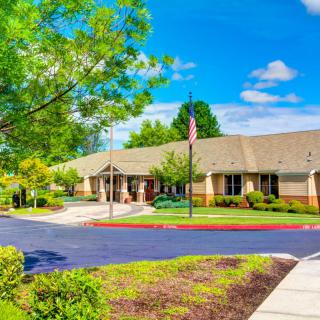 A bright and sunny day at a suburban building with a flagpole and lush green surroundings.