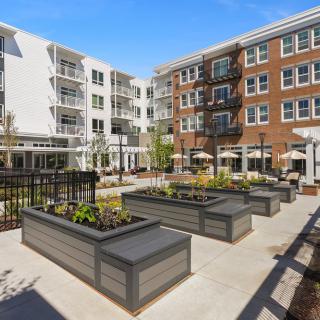 A modern apartment complex featuring a landscaped courtyard with raised planters.