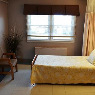 A minimalist bedroom with a single bed, chair, and window.