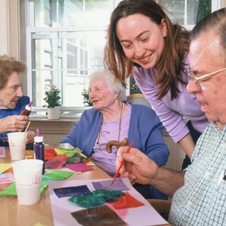 A group of senior citizens enjoy painting together in an art therapy session.