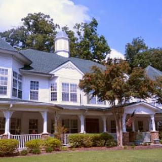 A large residential house with a spacious porch and surrounded by trees.
