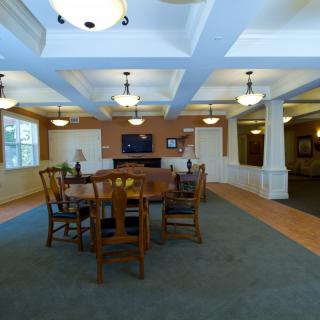 A cozy dining area with a central table and chairs, illuminated by ceiling lights.