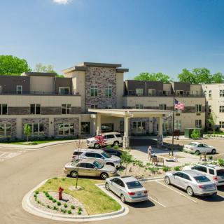 A modern healthcare facility with a spacious parking lot and cars parked in front of the building on a sunny day.