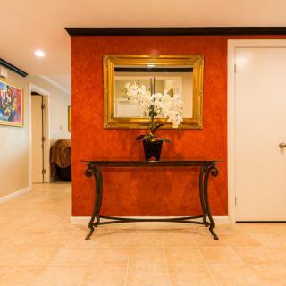 A warmly lit hallway with a decorative table, mirror, and an orchid centerpiece.