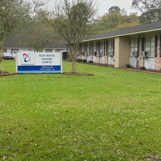 Exterior view of a building with a sign in a green lawn area.