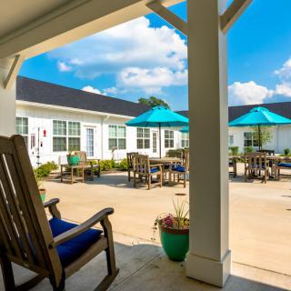 A sunny courtyard with patio furniture and blue umbrellas.