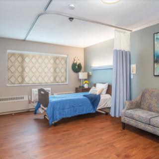 A well-organized hospital room featuring a bed, couch, and privacy curtains.