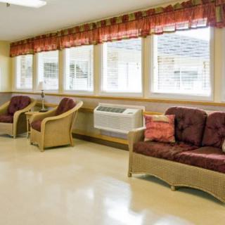 A cozy waiting room with padded chairs and a sofa facing large windows adorned with curtains.