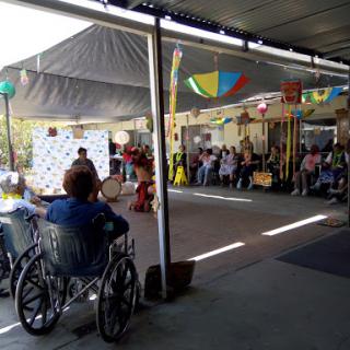 An outdoor community event with people gathered under colorful tents.
