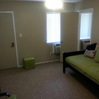 A simple, minimalist room with a bed and two windows.
