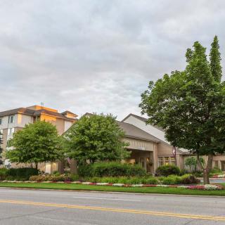 A suburban scene with a building surrounded by trees under a cloudy sky.
