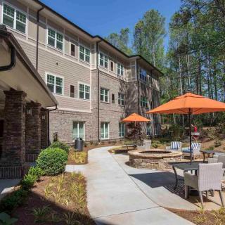A modern apartment complex with outdoor seating and vibrant patio umbrellas along a landscaped pathway.