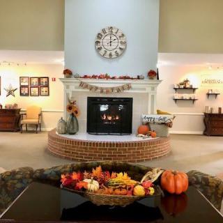 A cozy living room decorated for autumn, featuring a fireplace adorned with pumpkins and fall-themed ornaments.