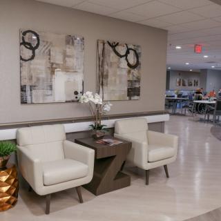 A modern lobby area featuring two chairs, a side table, and abstract artwork on the wall.