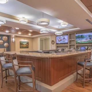 A modern bar interior with wooden decor, seating, and televisions.