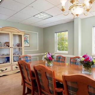 A well-furnished conference room with a long wooden table, surrounded by chairs and adorned with floral arrangements.
