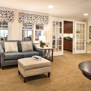 A cozy living room with a comfortable sofa, elegant window treatments, and a warm carpet.
