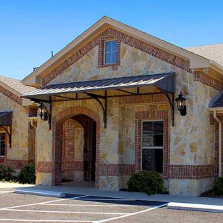 Stone facade office building with an arched entrance and awning.