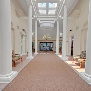 A spacious hallway with grand columns, seating areas, and a skylight illuminating the interior.