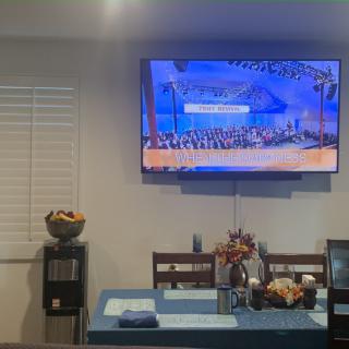 A modern living space with a wall-mounted TV above a dining area.