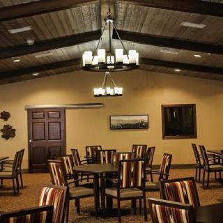 A cozy restaurant interior featuring wooden chairs and tables under a decorative chandelier.