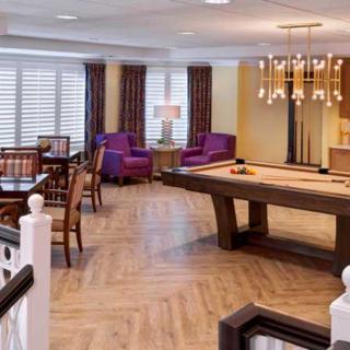 A cozy game room featuring a pool table, comfortable seating, and elegant lighting.
