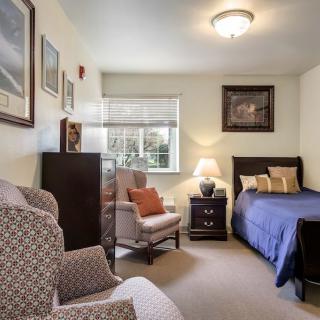 A cozy bedroom with a single bed, armchair, and decorative elements.