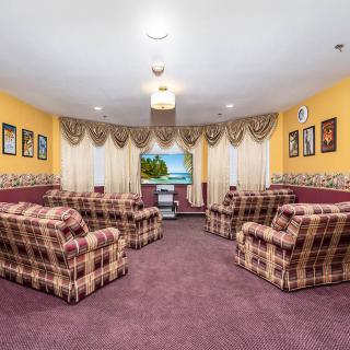 A cozy living room with plaid sofas, a television, and decorative curtains.