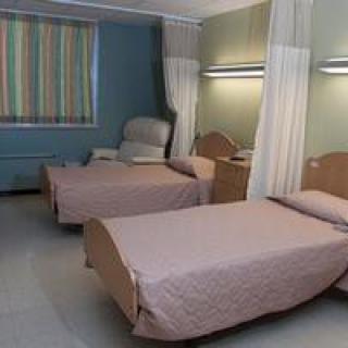 A hospital room with two neatly arranged beds, separated by privacy curtains.