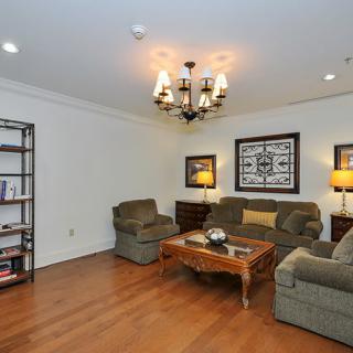 A cozy living room with comfortable seating, a wooden coffee table, elegant lighting, and decorative artwork.
