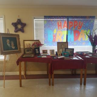 A festive birthday celebration setup featuring various photos and a colorful 'Happy Birthday' banner.
