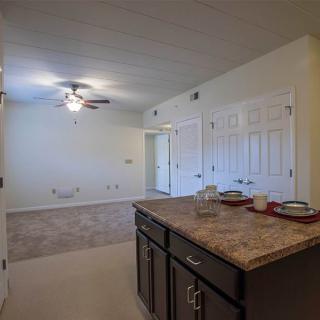A spacious apartment interior featuring a kitchen with a countertop and a ceiling fan in the dining area.
