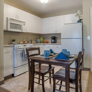 A cozy kitchen with a dining area featuring modern appliances and a neatly set table.