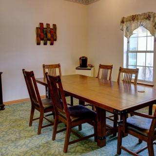 A cozy dining room with a wooden table and six chairs, featuring a large window and decorative elements.