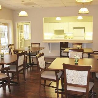 A cozy dining room with several tables and chairs, adjacent to a kitchen area.