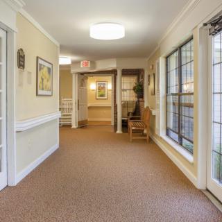 A well-lit hallway with large windows and carpeted flooring.