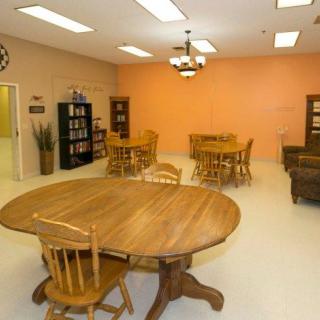 A cozy room with wooden tables and chairs, bookshelves, and warm lighting.