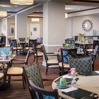 A cozy dining area with neatly arranged tables and chairs, featuring elegant decor.