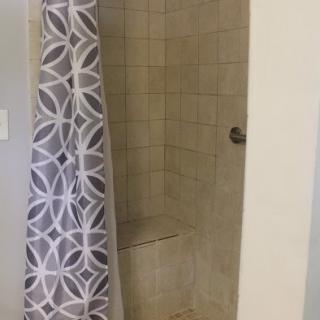 A tiled shower with a patterned curtain.