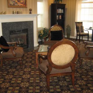 A cozy living room with a fireplace, armchairs, and a coffee table.
