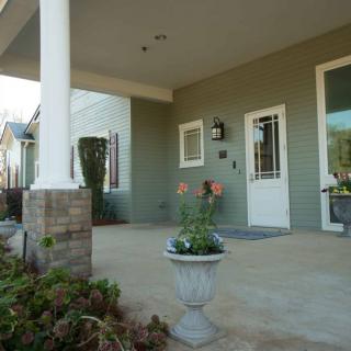 A welcoming house entrance with a spacious porch adorned with potted plants and white columns.