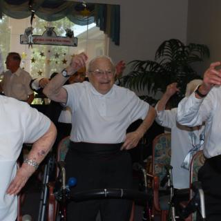 A group of elderly individuals participating in a group exercise at a nursing home.